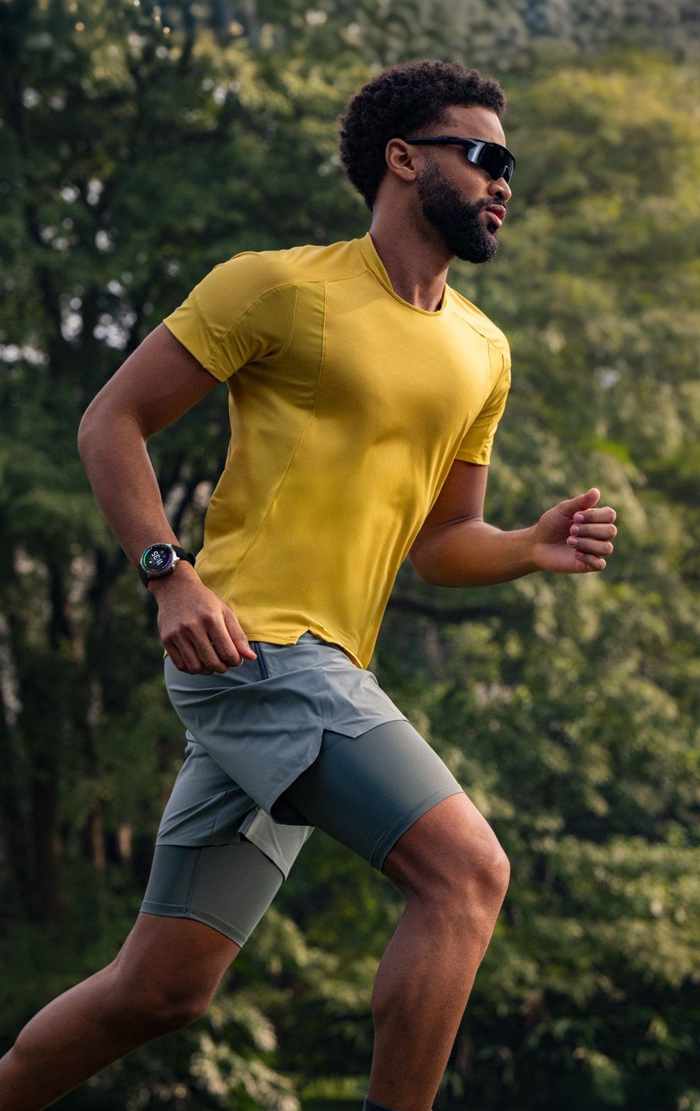 Un coureur en t-shirt jaune en pleine foulée dans un sous-bois, Moto Watch Ultra au poignet
