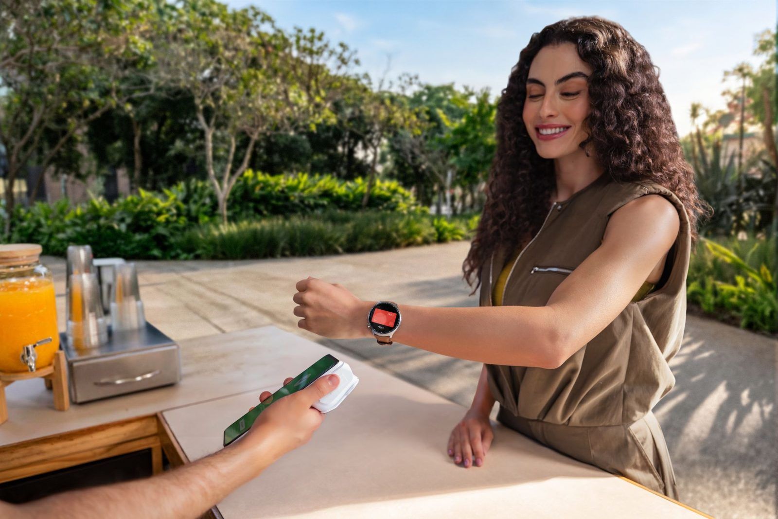 Une femme paie avec sa Moto Watch Ultra au comptoir d’un café en terrasse
